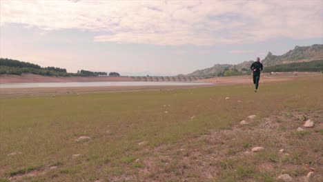 persona corriendo en una playa de un pequeño lago
