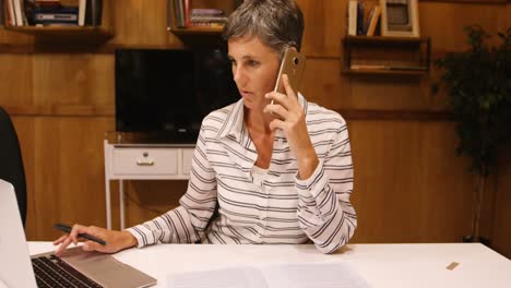 mujer de negocios tomando un teléfono móvil mientras usa una computadora portátil 4k