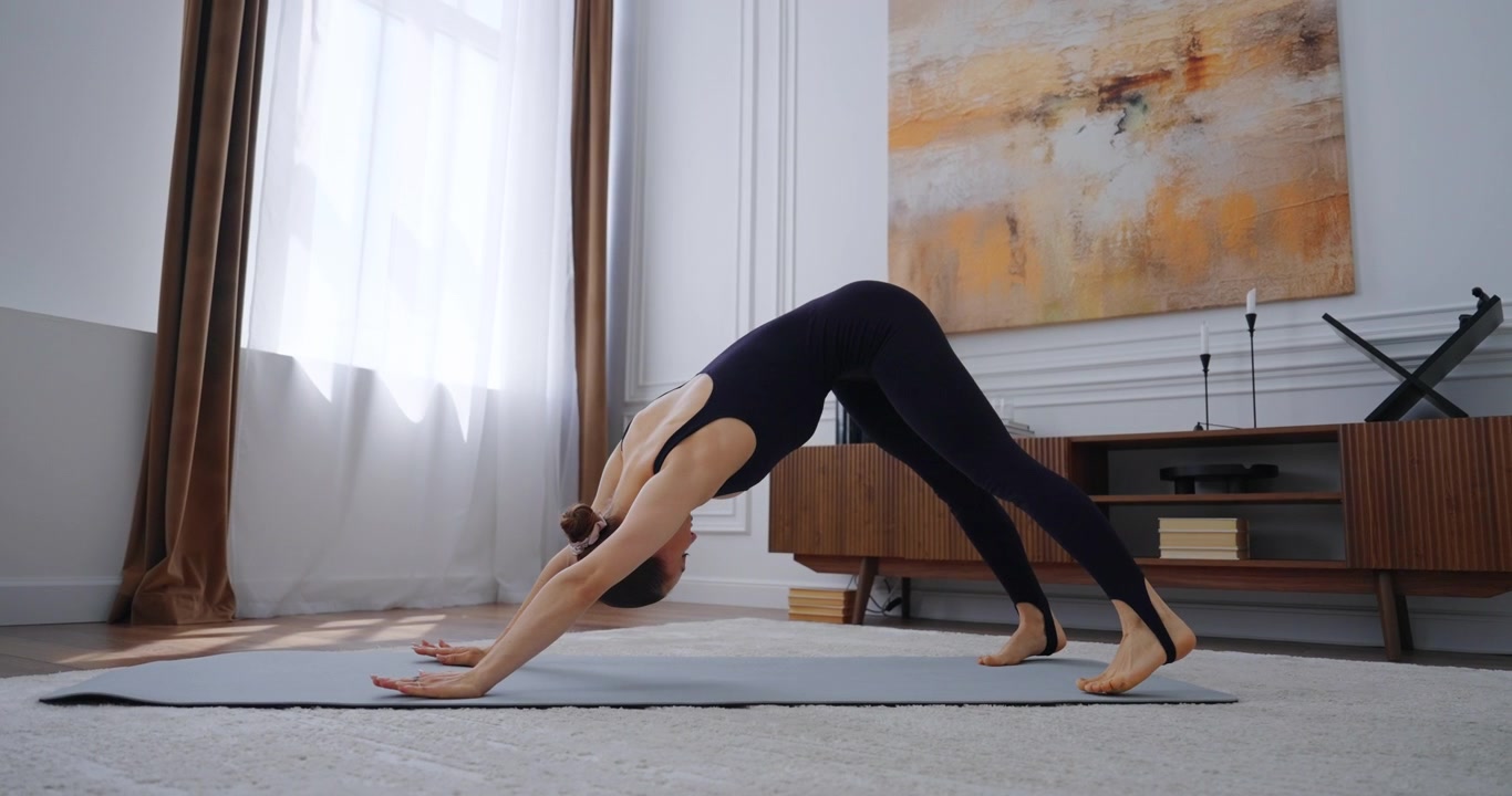 Junge Frau praktiziert Yoga-Posen auf der Matte zu Hause