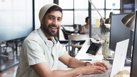 young man with beard working on a computer in a modern office setting for his business