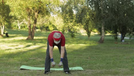abuelo senior haciendo ejercicios de fitness con pesas durante la pandemia de coronavirus solo en el parque
