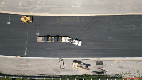 Suburban-Utah-aerial-view-Birdseye-over-heavy-truck-driving-along-asphalt-road-construction