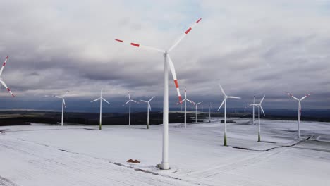 aerial trucking shot of beautiful ecological wind turbines farm for green energy during frosty and iced winter landscape at daytime