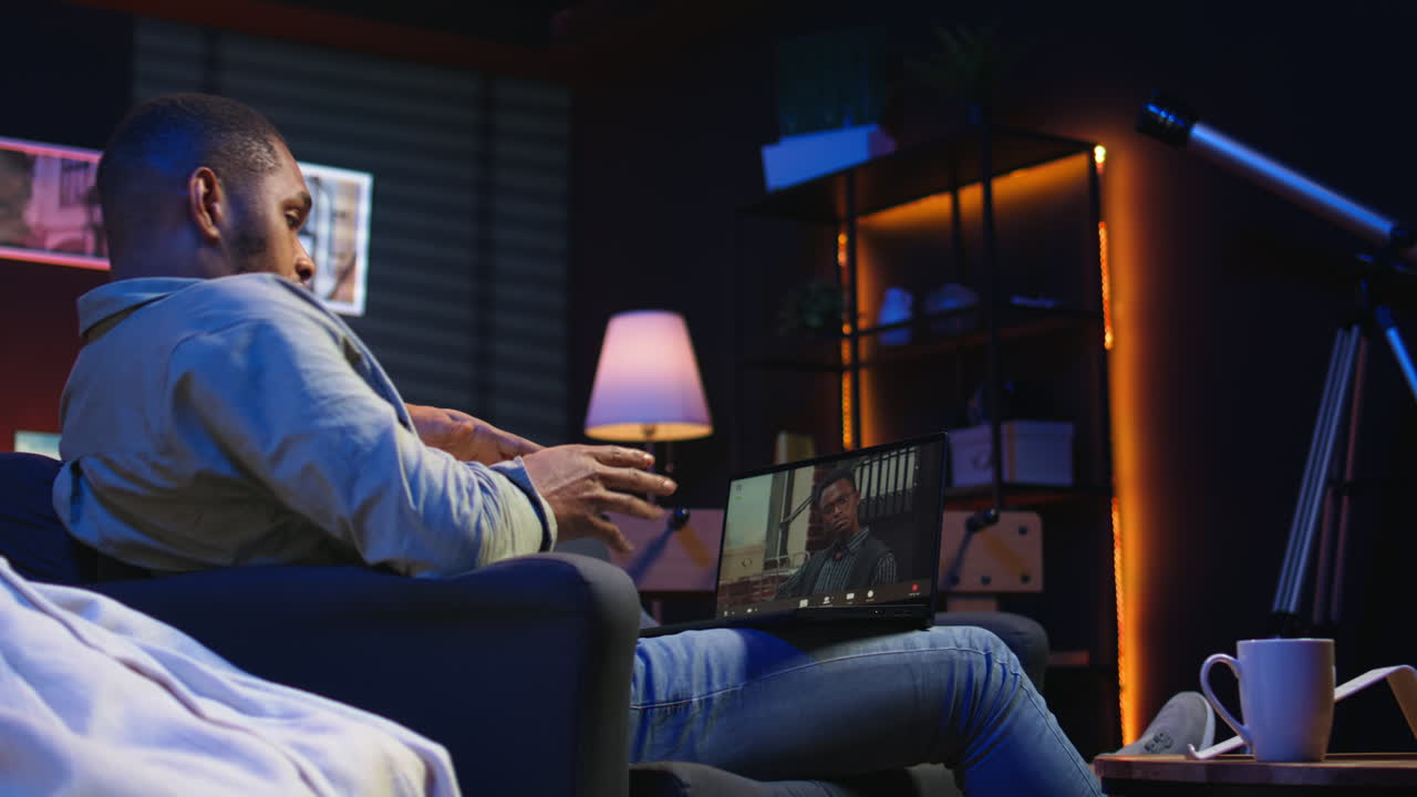 Vertical Video Focused black guy smiling and waving during a web conference in his living room