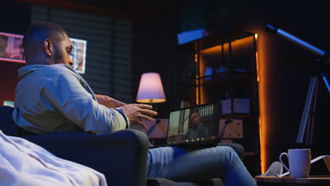 vertical video focused black guy smiling and waving during a web conference in his living room