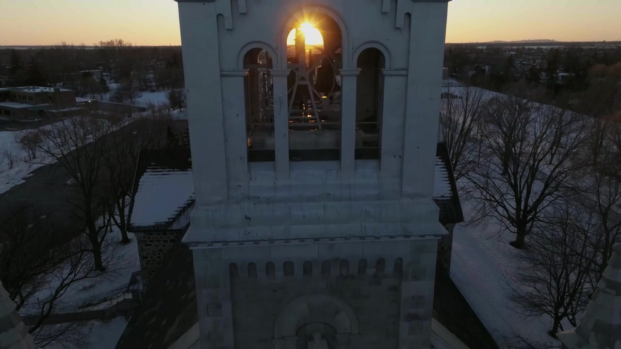 Drone daler ned fra tårnet til kirkens hovedklokker i Chambly, Quebec, Canada om vinteren, den forreste del og kirkegården.