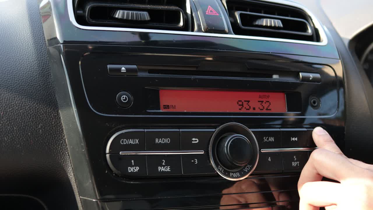 Close up image of driver's hand press button on car radio, listening music during trip