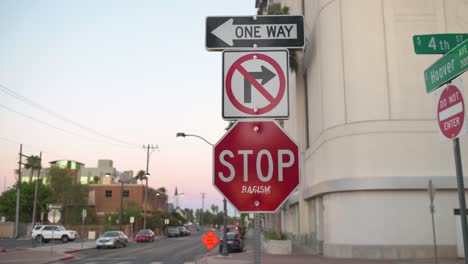 Stop sign at intersection with sticker that says racism on it on a windy day in Las Vegas, Nevada