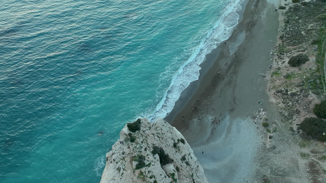 воздушный вид на прибрежный ландшафт в сумерках, демонстрирующий извилистую дорогу рядом с спокойным пляжем с мягкими волнами и крутым краем скалы с видом на море