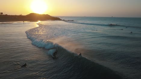 aerial view following a surfer crashing in a wave, during sunset, at the coast of talara, in peru - tracking, drone shot