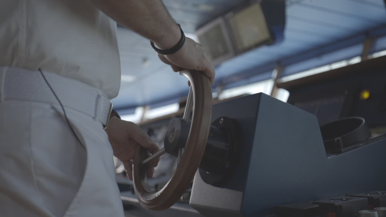 primer plano de las manos del capitán en el volante de un crucero conduciendo el barco en la cabina
