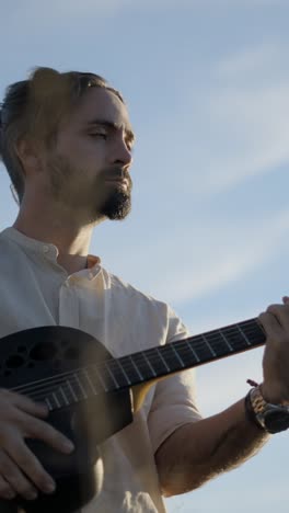hombre tocando la guitarra acústica al aire libre
