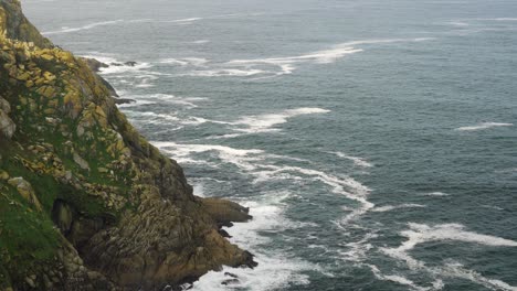 static shot of a huge cliff with the sea eroding the rocks of the shore