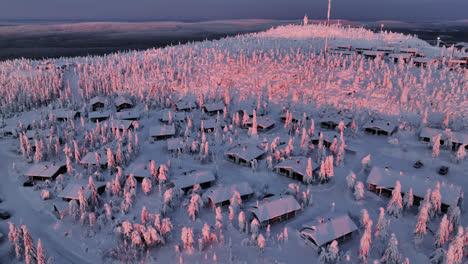 drone dando vueltas alrededor de cabañas nevadas en la cumbre de iso-syote fjell, amanecer en finlandia
