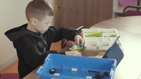 children intently focused on assembling parts from a robotics kit, with a tablet displaying instructions, promoting stem learning and creativity