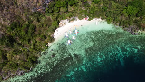 vista desde arriba de un avión no tripulado cinematográfico de una playa de arena tropical con barcos en la orilla en palawan filipinas, aérea