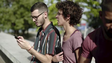 una joven pareja sonriente usando un teléfono inteligente en la calle.