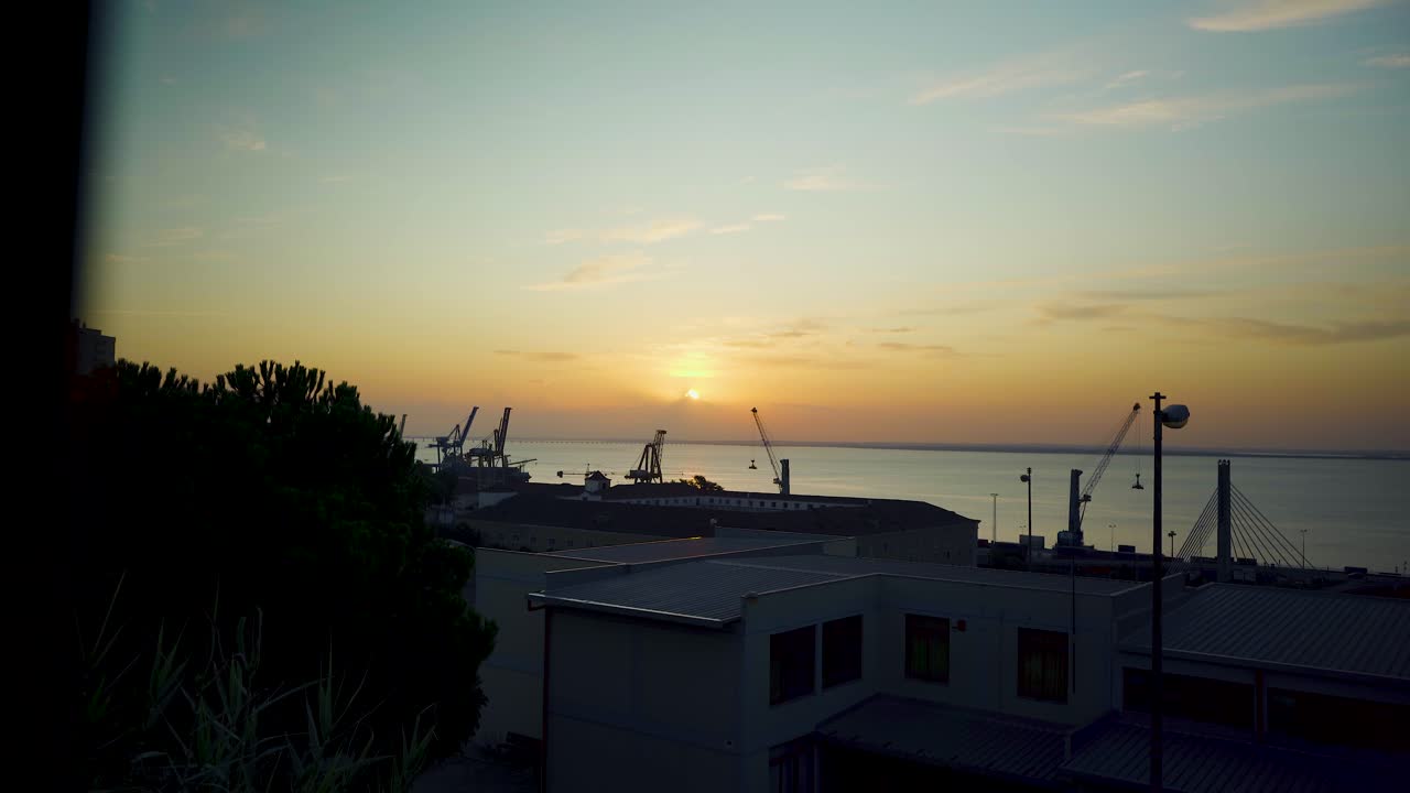 녹슨 울타리를 통해 크레인 실루엣으로 리스본 항구 일출