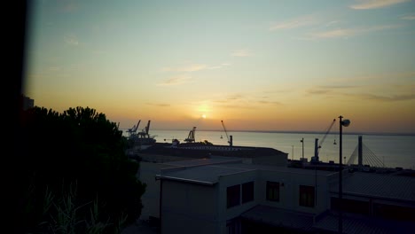 amanecer del puerto de lisboa con silueta de grúas a través de cercas oxidadas
