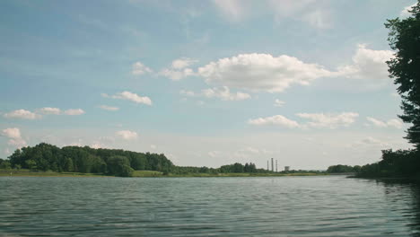 coal power plant in distance from peaceful lake view, pan left