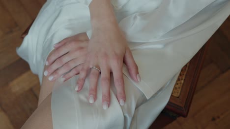 close-up of a bride's hands with a wedding ring on a white dress