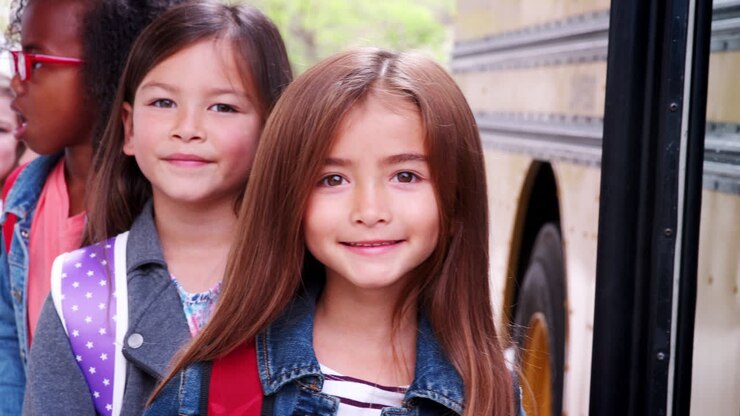 Duas meninas na frente da fila do ônibus escolar.