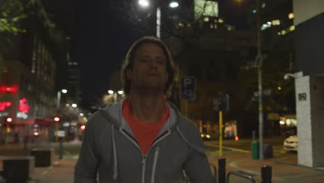 hombre caucásico haciendo deporte en una calle por la noche