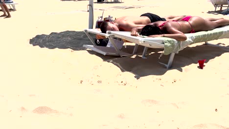 tanned couple peacefully rests on the sandy beach, basking in the warmth of the sun during their vacation