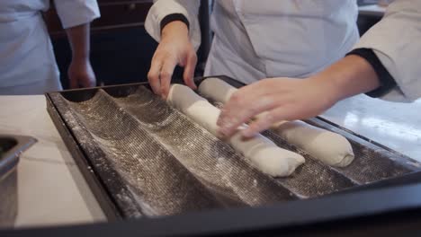 chef puts the bread dough into black baking tray