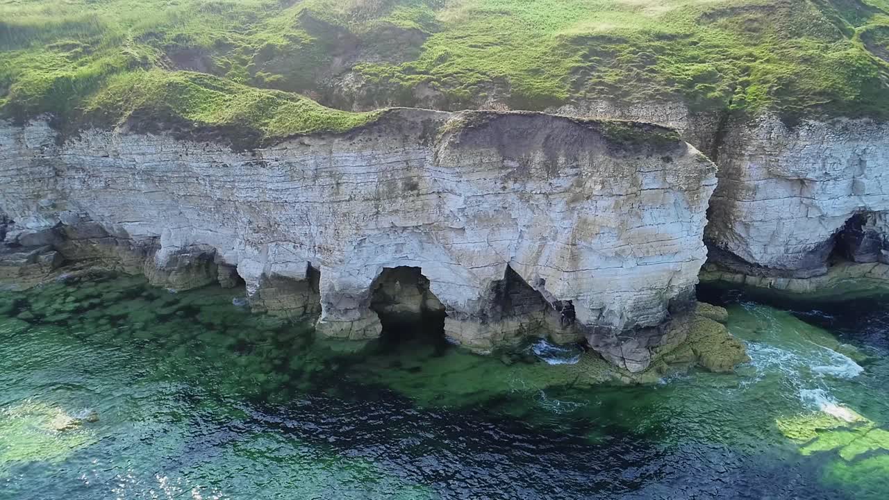 Beautiful chalk coastal cliffs at low tide, with visible cracks showing in the cliff faces