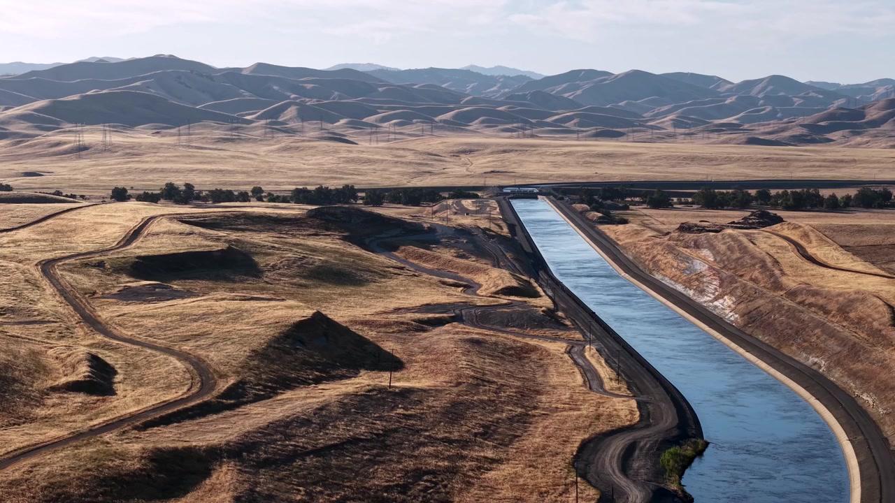 Acqua del canale dell'acquedotto della California che scorre attraverso il paesaggio desertico secco e arido. Fiume artificiale agricolo che fornisce acqua ai terreni agricoli per l'irrigazione nelle campagne.