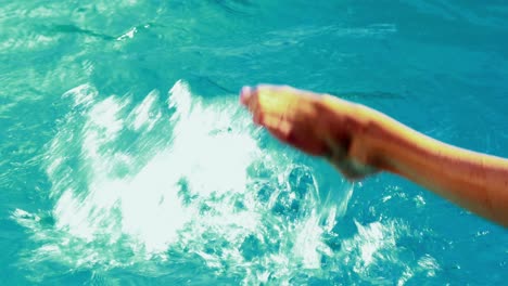 women splashing her legs in swimming pool