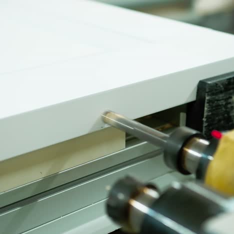 furniture production. modern machine tool for making doors. industrial equipment making hole in wooden board. close-up.