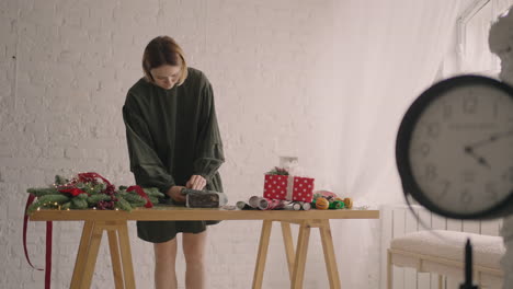 mujer joven empacando regalos de navidad para sus amigos y familiares una mujer envuelve sus manos alrededor de una caja en un adorno de navidad papel de regalo adornos navideños preparándose para la temporada festiva.