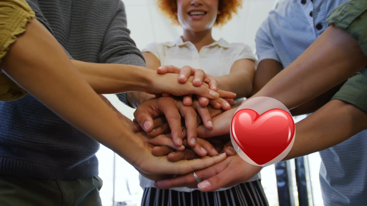 Icona di cuore rosso sulla parte centrale di diversi colleghi d'ufficio che uniscono le mani in ufficio
