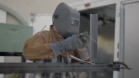 welder using stick welder removes mask to check his work, slow motion