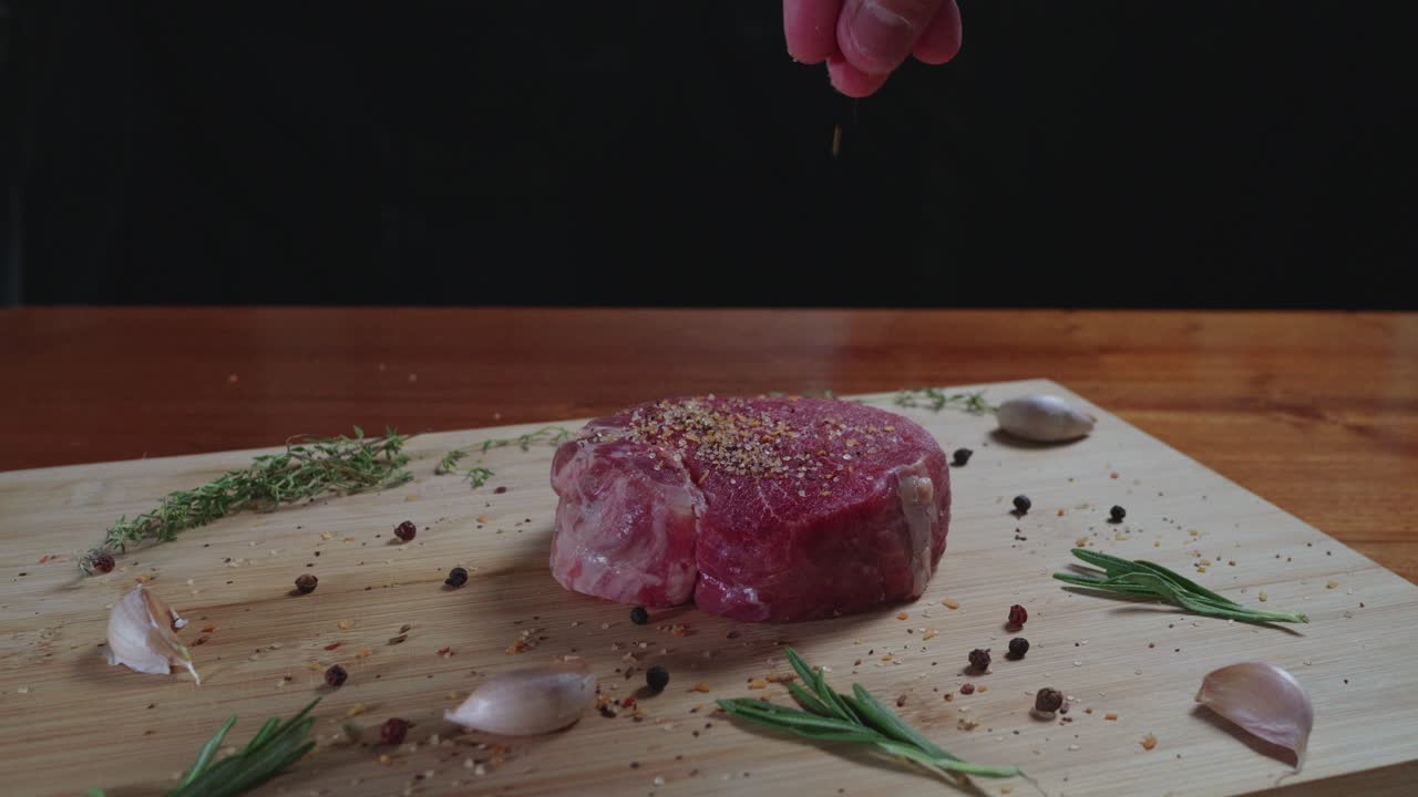 Chef seasons tenderloin steak on a wooden cutting board, slow motion, close up