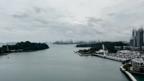 drifting above keppel harbour, with a view of a shipping yard in the distance in singapore from a cable car - pov