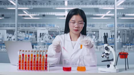 asian woman scientist making experiment with test tube, typing on a laptop then having a headache in the laboratory with microscope. working in the lab analyzing her finding sample test tube