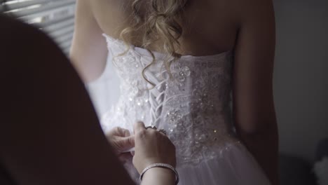 helping bride to tie her dress