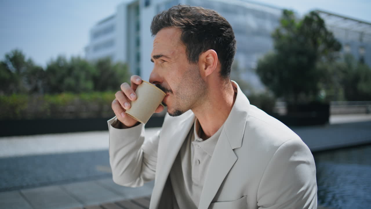 Mand drikker kaffe på solrig plads tæt på. Forretningsmand nyder frokost.