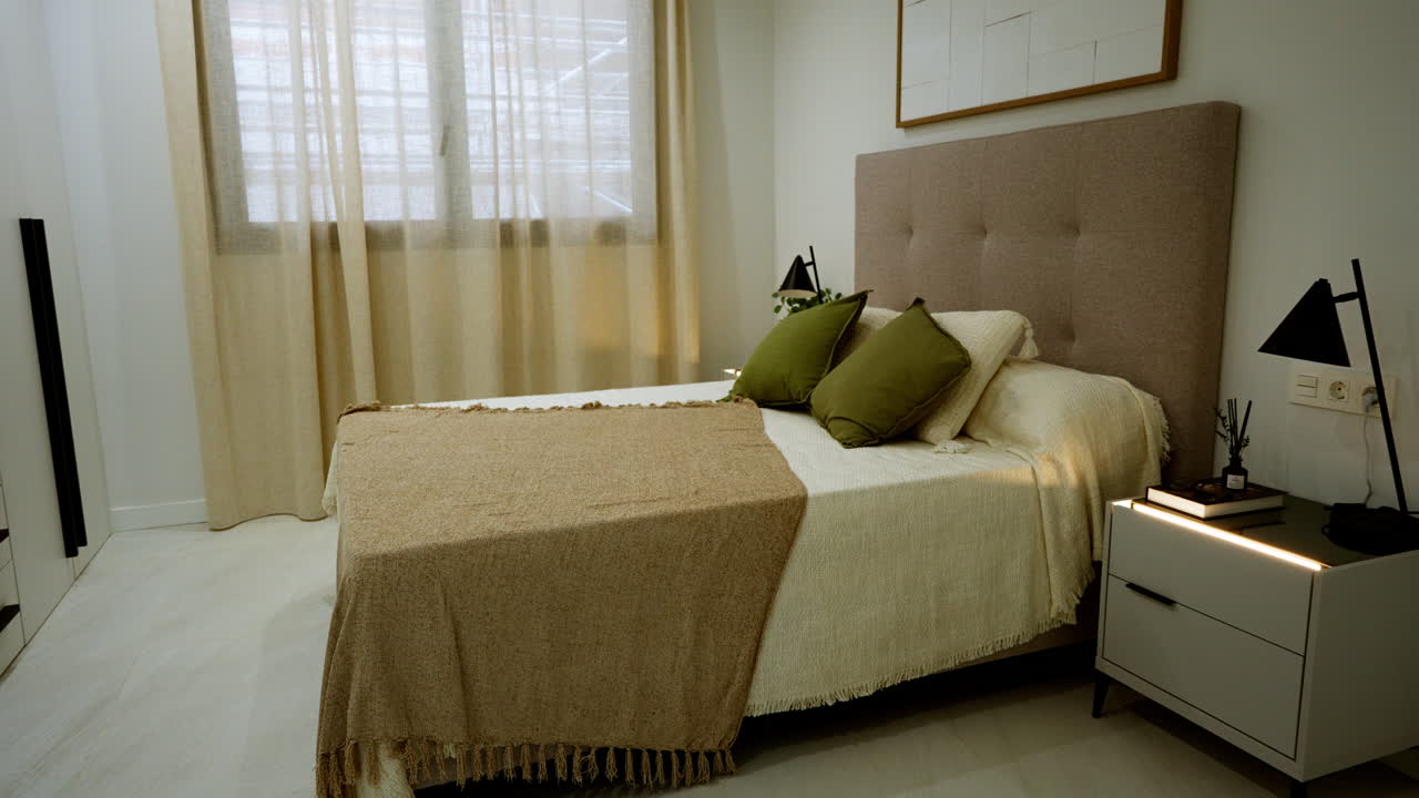 Interni di una camera da letto contemporanea in un moderno appartamento di lusso, caratterizzati da toni neutri, luce naturale soffusa e arredamento minimalista. Spazio residenziale allestito ideale per il marketing immobiliare o per affitti