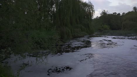 Toma-Panorámica-De-Agua-Espumosa-Que-Se-Vierte-En-Un-Gran-Estanque-Por-La-Noche-Cerca-De-Leamington-Spa,-Warickshire,-Inglaterra,-Reino-Unido.