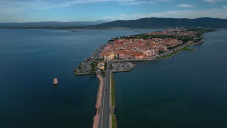 Cars-on-a-bridge-road-across-the-lagoon-toward-the-old-island-town-Orbetello-close-to-Monte-Argentario-and-the-Maremma-Nature-Park-in-Tuscany,-Italy,-with-water-reflections