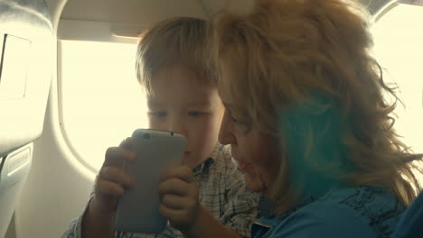 Niño-Y-Abuela-Entretenidos-Con-Teléfono-En-Avión