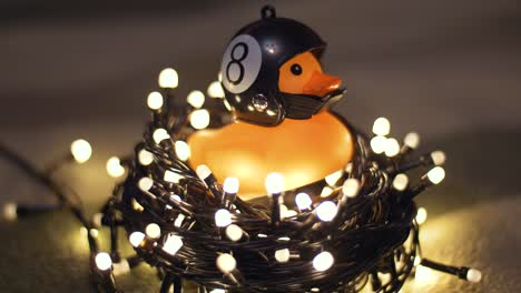 fotografía en primer plano de un pato de goma con un casco de motocicleta hecho a mano sobre el fondo de una guirnalda de navidad