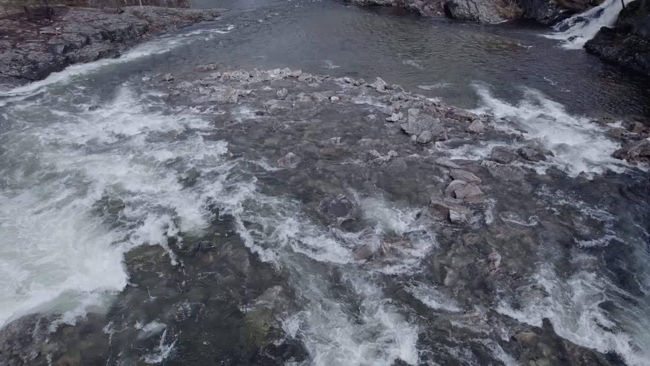 A large, mountain, rushing river flowing between rocks, aerial view