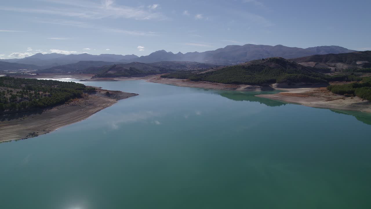 Lake with calm waters and the sky reflected in it. Mirror effect. Aerial view of a beautiful lake surrounded by mountains. Sky and clouds reflected in the lake waters. Granada. Spain