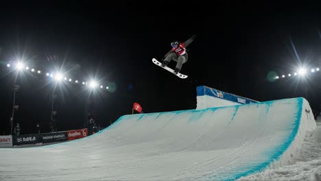 Spectacular Snowboard Performance Under Night Lights: A Skilled Athlete Executes Precision Tricks on a Halfpipe in an Electrifying Atmosphere
