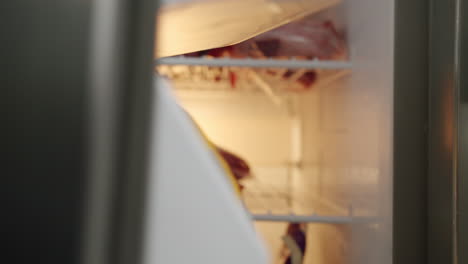 Close-Up-View-Of-Hand-Opening-Refrigerator-Door-And-Placing-Sealed-Red-Meat-Steak-Onto-Freezer-Shelf,-4K